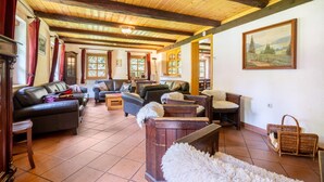 A spacious living area with wooden beams, leather sofas, and a large painting on the wall.