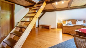 A wooden staircase leading to a loft bedroom with a bed and nightstand.