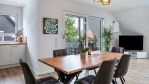 A modern dining area with a wooden table, dark chairs, and pendant lighting.