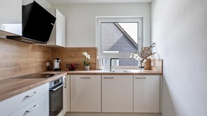 A modern kitchen with a built-in oven, a window, and a wooden countertop.