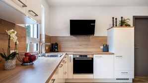 Eine moderne Küche mit Holzarbeitsplatte, eingebautem Backofen und einem Flachbildfernseher.