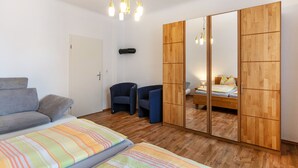 Ein Schlafzimmer mit einer Couch, zwei Sesseln, einem Bett, einem Kleiderschrank und einem Spiegel.