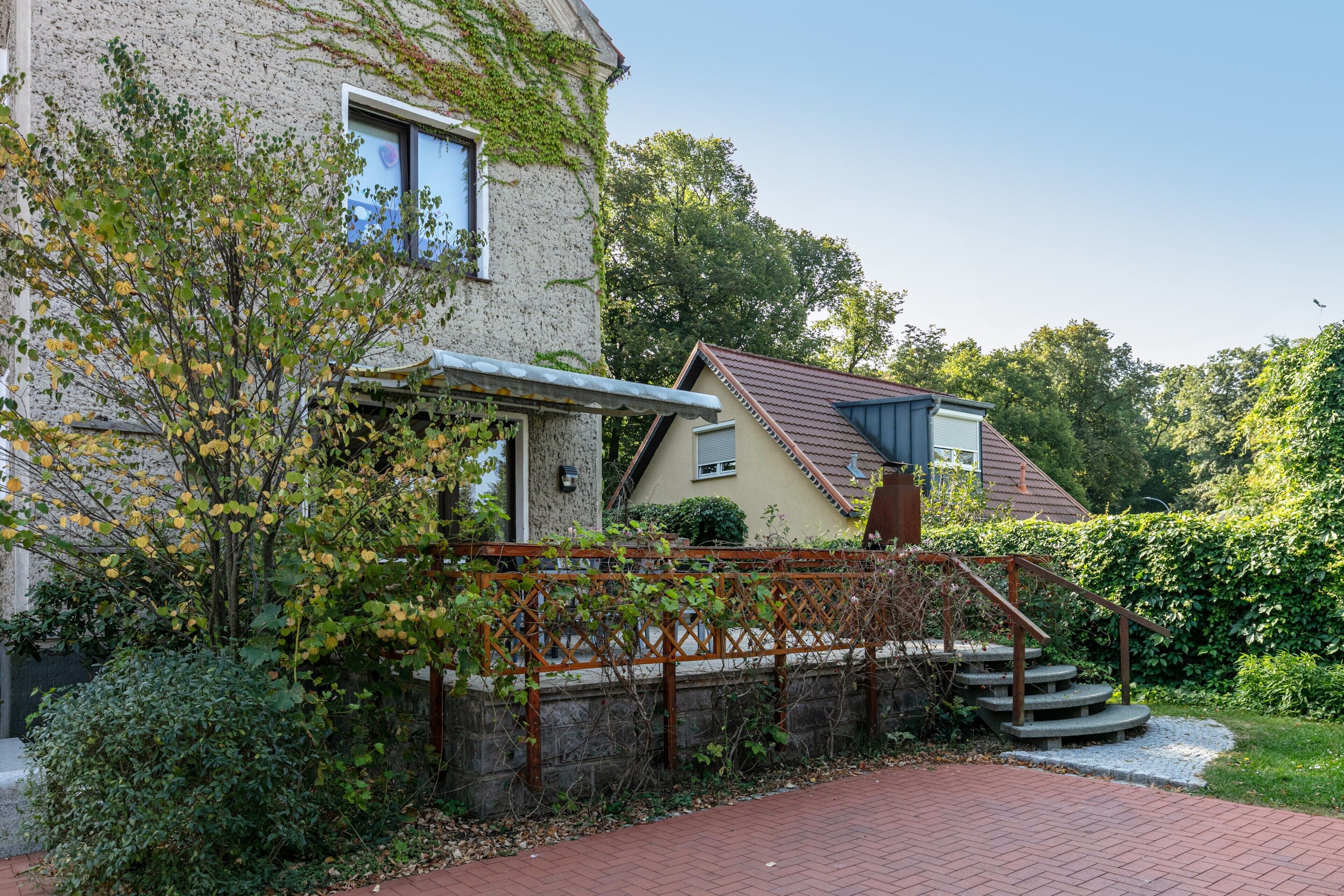 Een huis met een stenen gevel, een houten trap en een tuin.