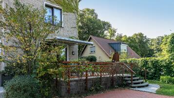 Een huis met een stenen gevel, een houten trap en een tuin.