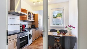 Eine moderne Küche mit Edelstahlgeräten, Holzschränken und einem Essbereich mit Tisch und Stühlen.