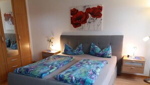 A bedroom with a bed, a nightstand, a dresser, and a painting of red flowers on the wall. - Apartment 'Waldesruh' with Private Terrace and Wi-Fi (Sölden)