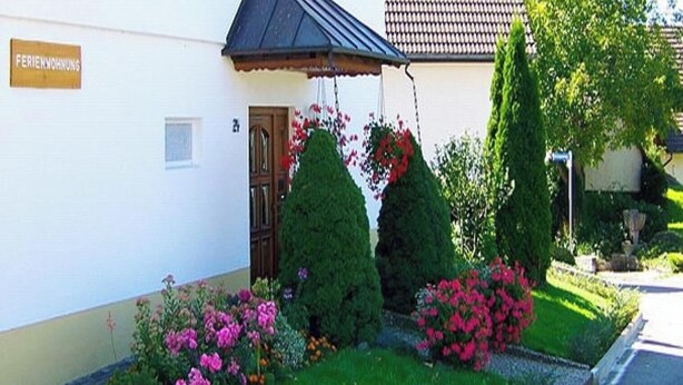 A building with a sign reading 'FERIENHOFNUNG' and a door. There are well-maintained bushes and flowers in front. - Apartment 'Waldesruh' with Private Terrace and Wi-Fi (Sölden)