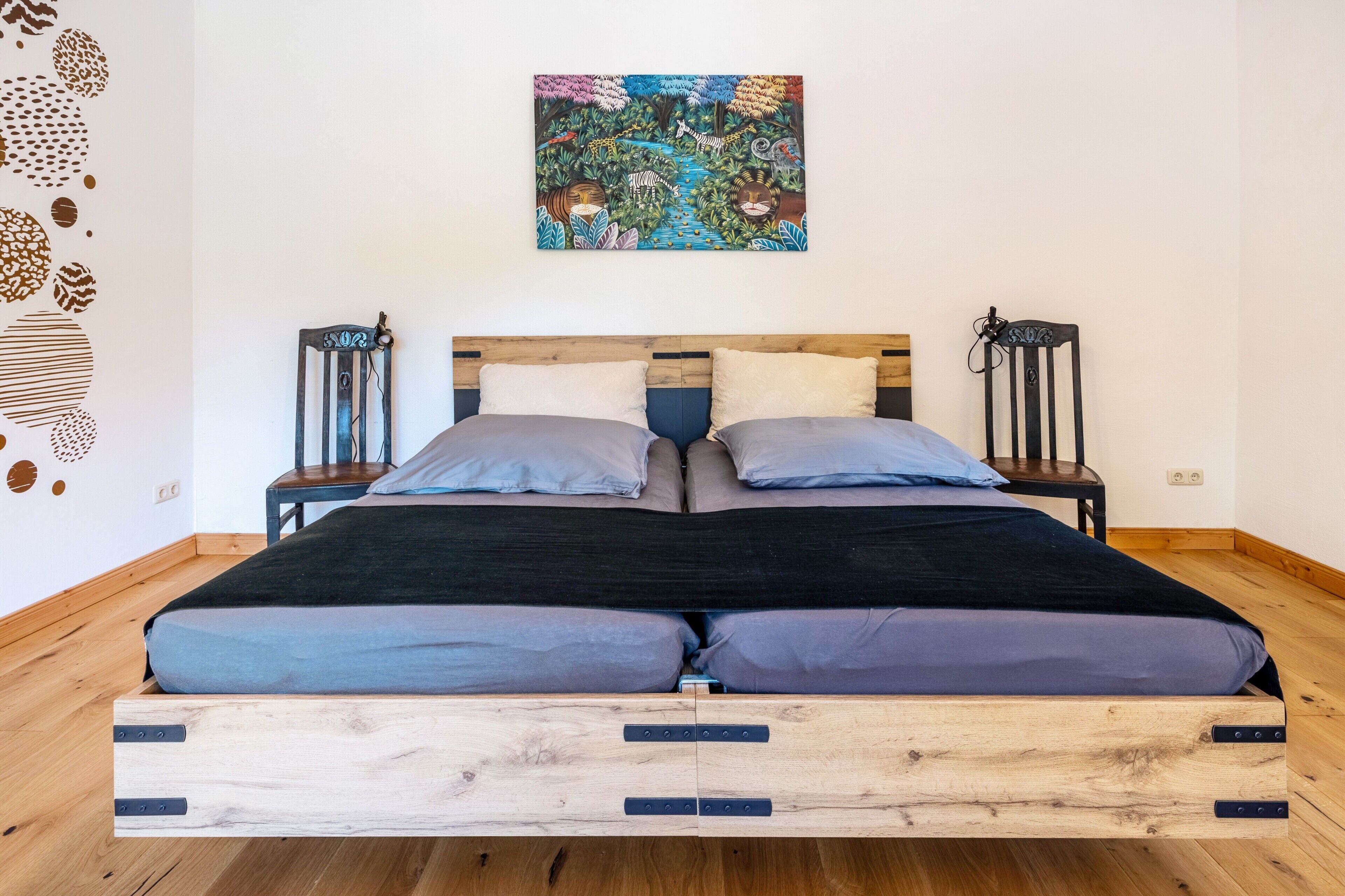 Un letto con una struttura in legno, due comodini e un quadro appeso al muro.