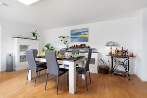 Una cocina moderna con comedor, muebles blancos y un cuadro en la pared.