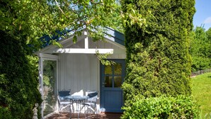 Un espace extérieur abrité, aménagé avec une table et des chaises, et entouré d’une végétation luxuriante.