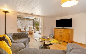 Un salon avec un canapé, une table en verre, un meuble en bois et un téléviseur.