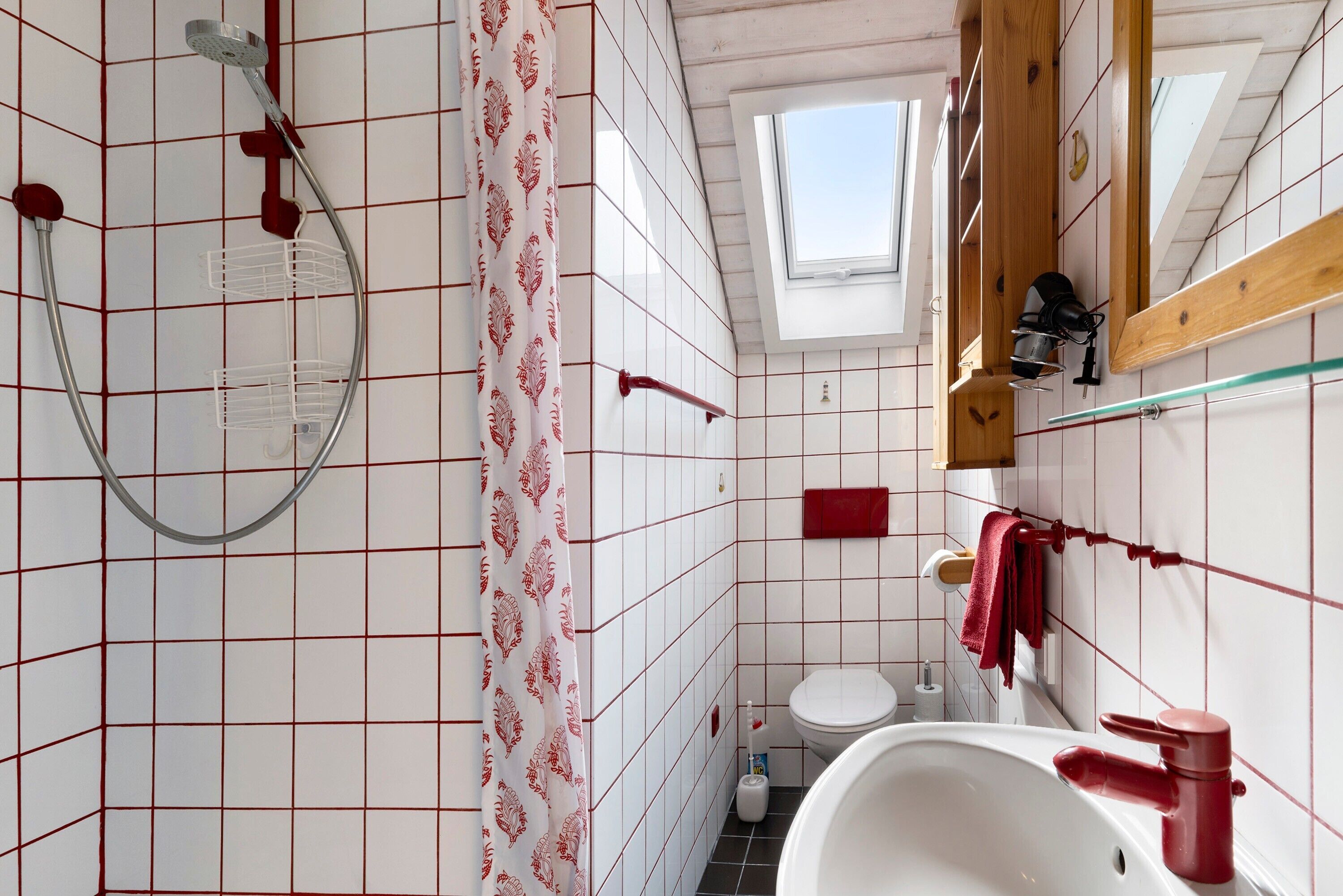 Ein Badezimmer mit Dusche, Toilette, Waschbecken und einem Oberlicht.