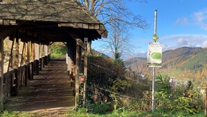 Un pasillo cubierto de madera que conduce a un refugio, con un cartel cercano.
