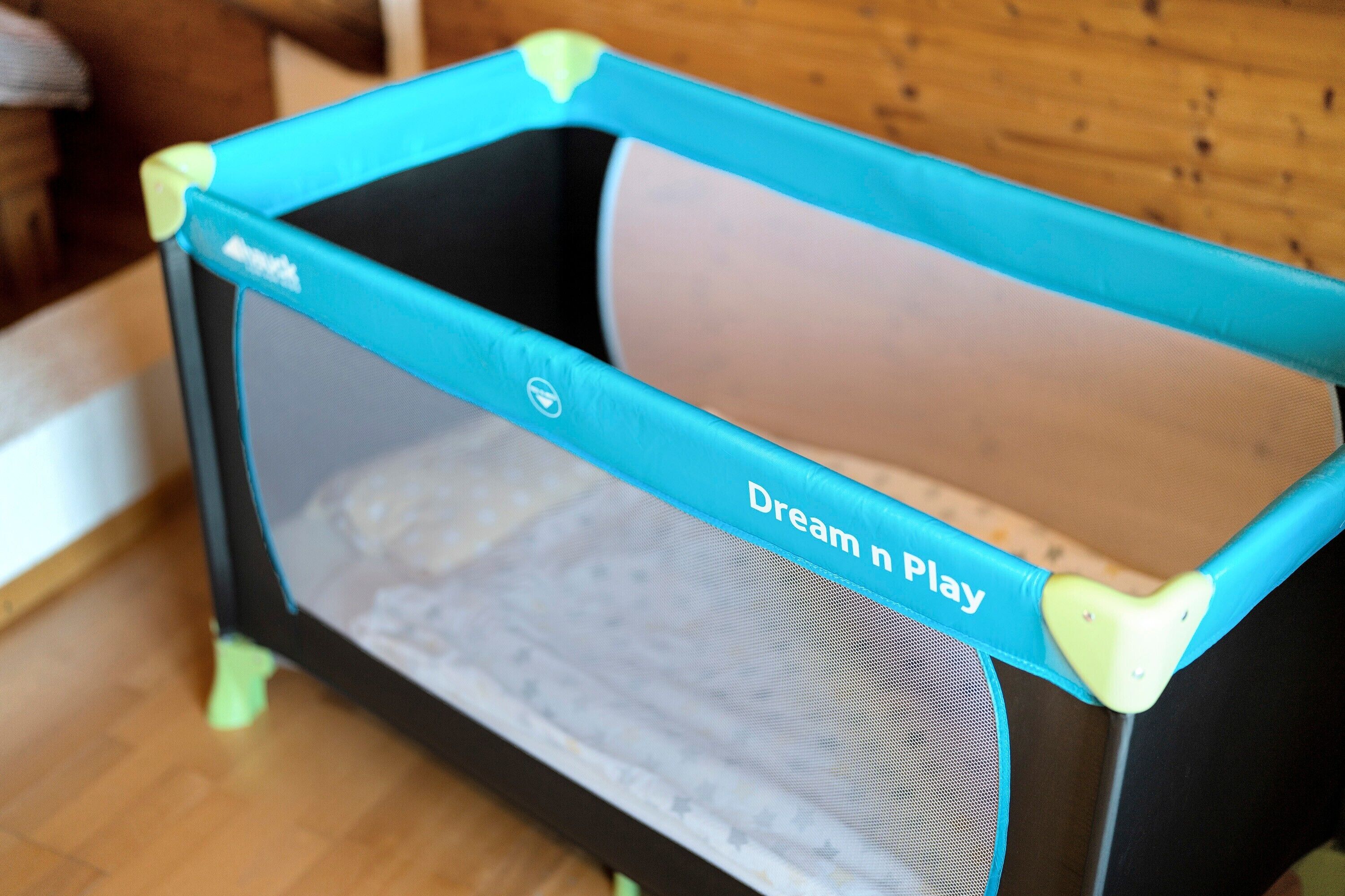 A portable playpen with a mesh bottom and a blue frame.