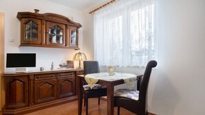Ein Essbereich mit einem Holztisch, Stühlen, einem Fernseher und einem Schrank.