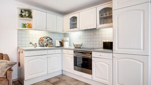 Eine Küche mit weißen Schränken, einer gefliesten Spritzschutzleiste, einer Kaffeemaschine und einer Mikrowelle.