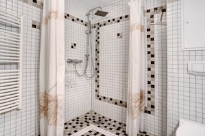 A shower with a white curtain, a handheld showerhead, and a wall-mounted faucet.