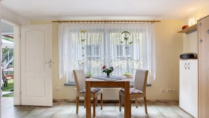 Ein Essbereich mit Tisch, Stühlen, einem Fenster mit Vorhängen und einem Schrank.