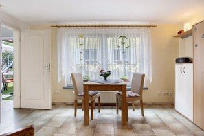 Un coin repas comprenant une table, des chaises, une fenêtre avec des rideaux et un meuble.