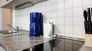 Una cocina con cafetera, hervidor y bloque de cuchillos.