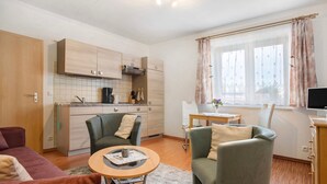 Un espacio habitable compacto con kitchenette, comedor y zona de estar con una mesita de centro.