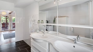 Een moderne badkamer met twee wasbakken, een grote spiegel en uitzicht naar buiten.