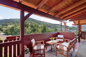 A wooden deck with a table and chairs, overlooking a mountainous landscape. - Apartment 'Vogtshaus De Luxe' with Mountain View, Private Terrace for 13 Guests (Gernsbach)