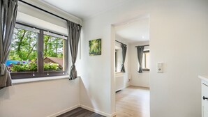 A room with a large window, a radiator, and a door leading to another room.