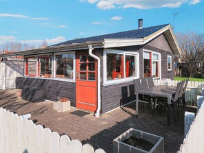 A house with a covered patio, a red door, and a fenced yard. - 5 Person Holiday Home in Hals (Hals)
