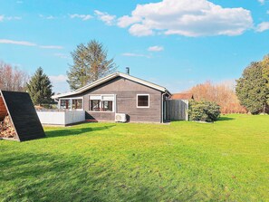 A single-story house with a sloped roof, a deck, and a well-maintained lawn. - 5 Person Holiday Home in Hals (Hals)