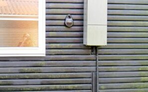 A window with a view of a wooden deck and a metal doorbell. - 5 Person Holiday Home in Hals (Hals)