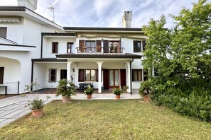 A two-story house with a balcony, potted plants, and a small patio area.