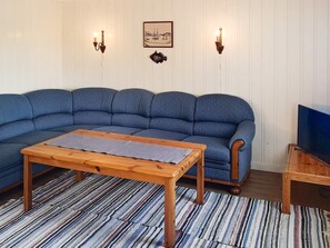 Ein Wohnzimmer mit einem blauen Sofa, einem Holztisch und einem Streifenmuster-Teppich.
