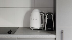 Eine Küche mit grauen Schränken, einer weißen Arbeitsplatte, einer Kaffeemaschine und einem Toaster.