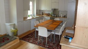 Una cocina compacta con armarios blancos, una mesa de comedor con sillas, una alfombra pequeña y un mueble de madera.