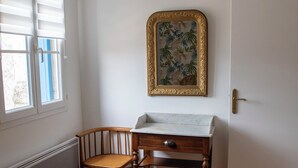 Slaapkamer met een bed, een stoel, een bureau, een radiator en een raam met jaloezieën.