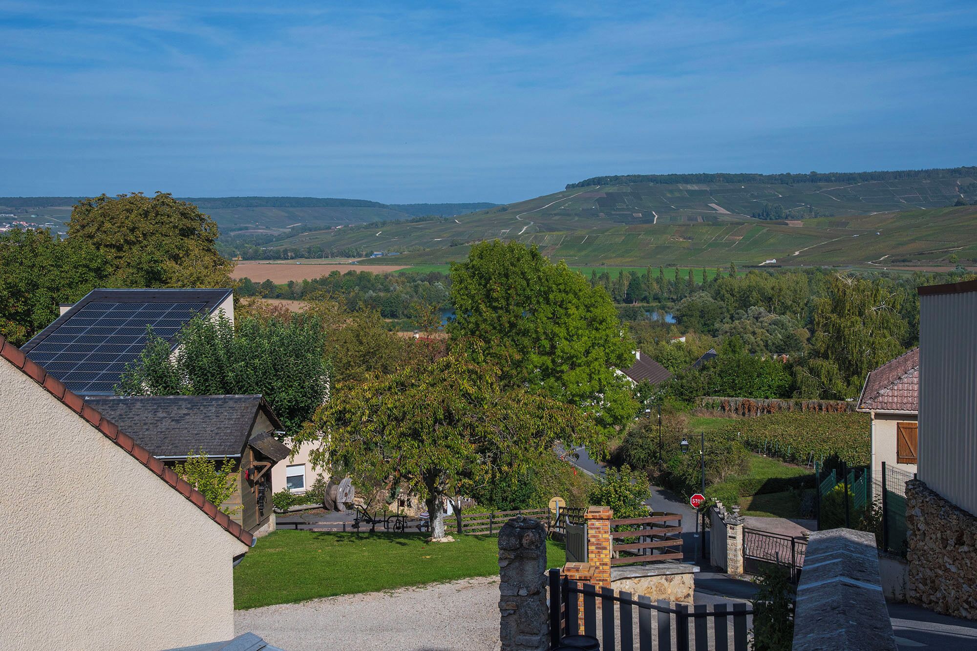 Ein Wohngebiet mit Häusern, einem Steintor und einer Aussicht auf sanfte Hügel in der Ferne.