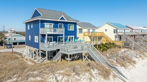 Ein Strandgrundstück mit einem zweistöckigen Haus, inklusive Balkon, einer Holzterrasse und einer Treppe zum Strand.
