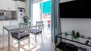 A modern kitchen with white cabinets, a built-in microwave, and a dining area with a white table and chairs. - 523 center Playa las Americas, pool and wifi (Playa de las Américas)