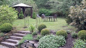 A garden with a gazebo, a table with chairs, and a stone staircase. - Cosy Apartment in Harz (Kassel)