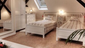 A bedroom with two beds, a skylight, and a white wardrobe. - Cosy Apartment in Harz (Kassel)