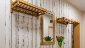 Een houten wastafelmeubel met een spiegel, een klein plantje en een houten plank.