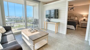 Ein geräumiger Balkon mit Glastür, einem Holztisch und einer Couch.