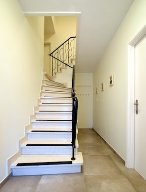 Una escalera con peldaños blancos y balaustres negros que lleva a una plataforma.