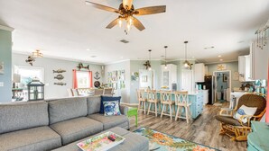 A spacious living room with a gray sectional sofa, a dining area with a wooden table and chairs, and a kitchen in the background. - 1 Mi to Marina: Rockport Vacation Rental (Rockport)