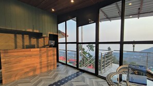 Un espace d’accueil doté d’un bureau en bois, de grandes fenêtres et d’un parquet disposé en motif chevrons.