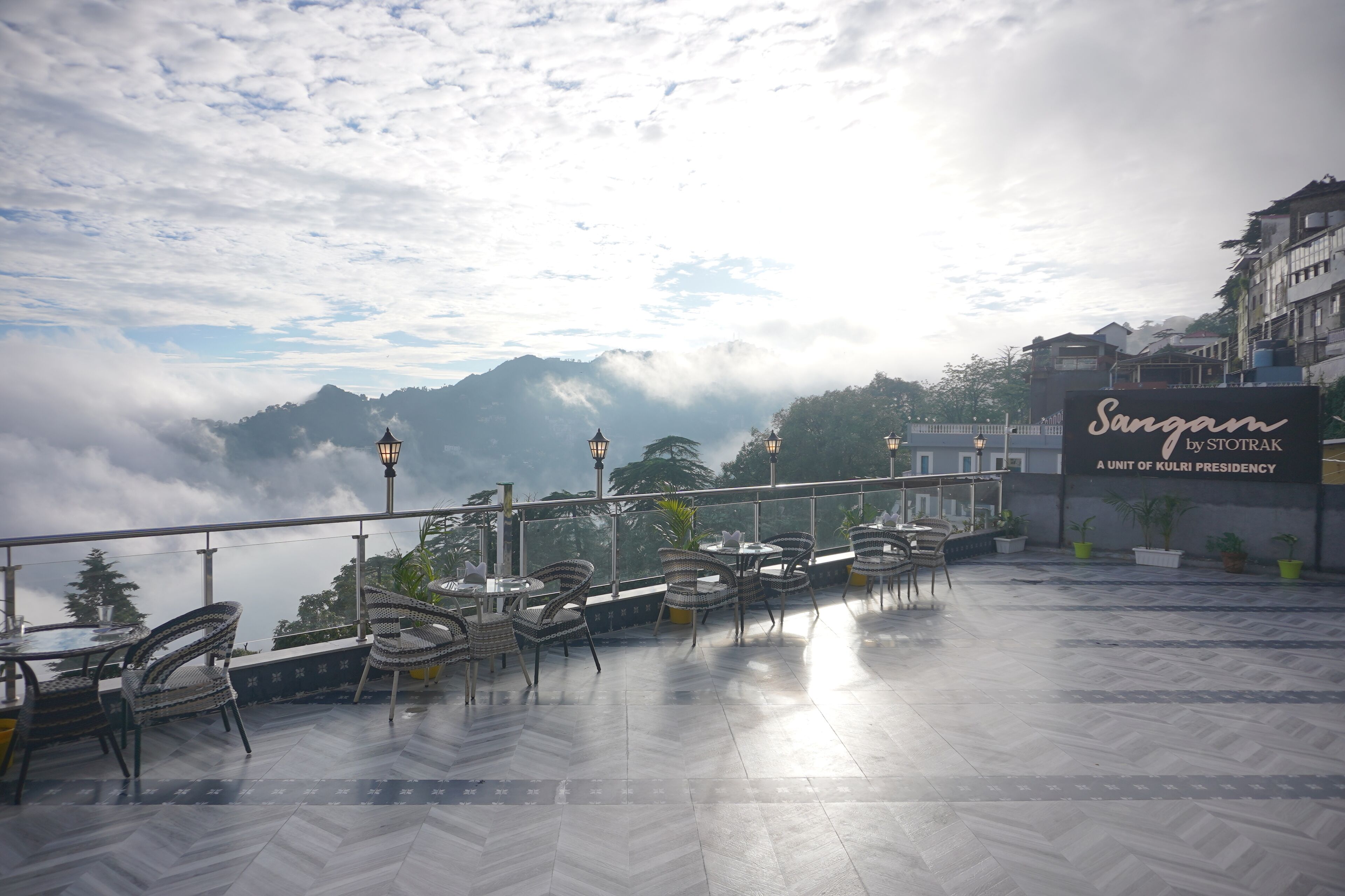 A terrace with tables and chairs, overlooking a mountainous landscape.