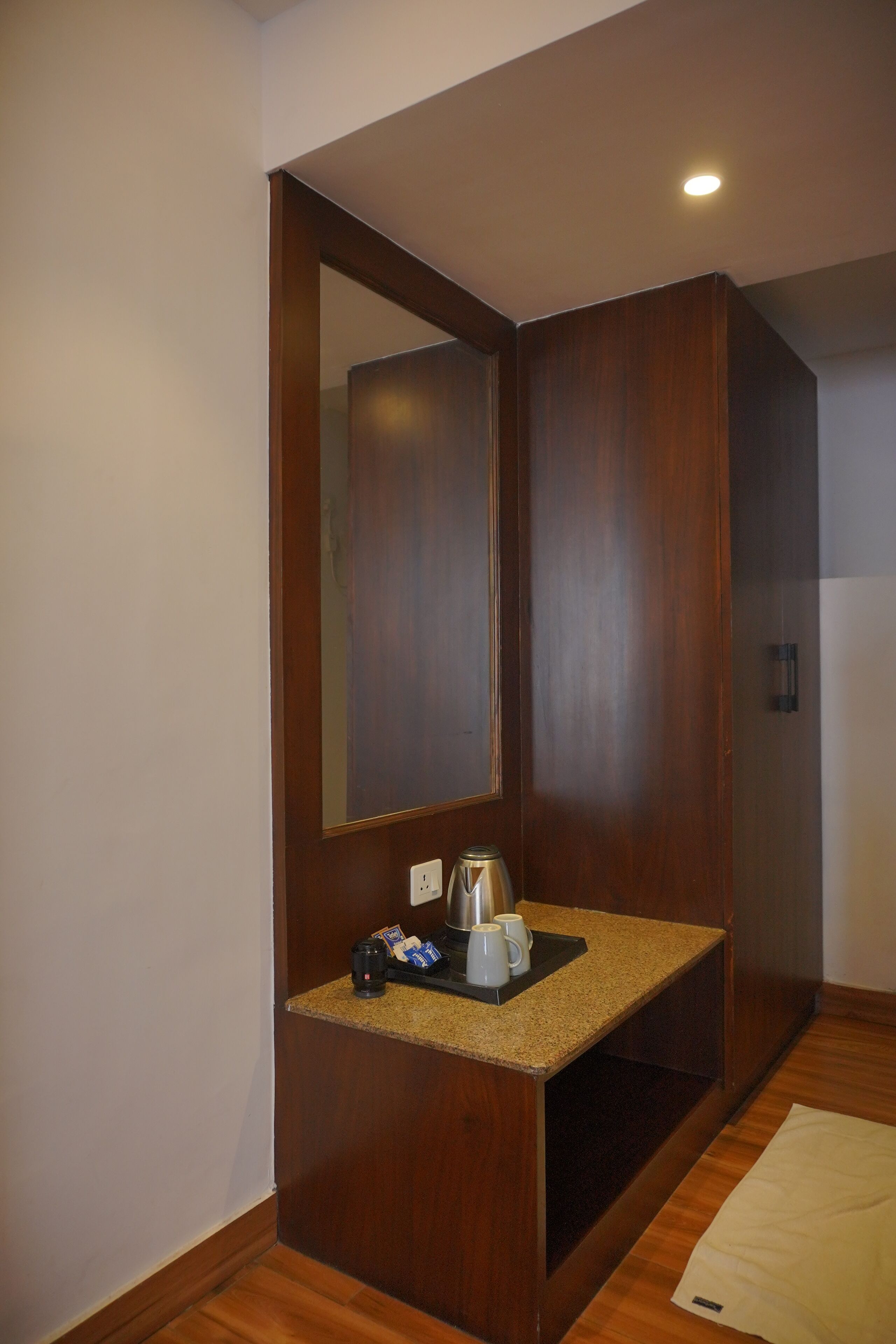 A small kitchenette with a countertop, a coffee maker, and a mirror.