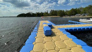 Un bote amarrado en un muelle, con cielo despejado y una costa lejana.