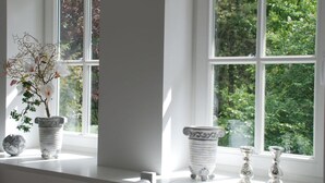 A room with a large window, white walls, and a white bench. There are three white vases on the bench. - Apartment at the Eichenpark (Egestorf)